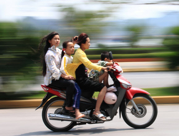 Foto de 2 mujeres y una niña a toda velocidad en una motocicleta - Barrido fotográfico