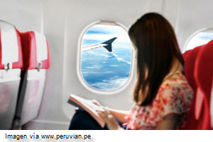 Pasajer sentada cómodamente y leyendo durante vuelo de Peruvian Airlines