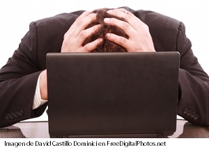 Imagen de hombre agachado en su computadora tocándose la nuca - Depresión y ansiedad